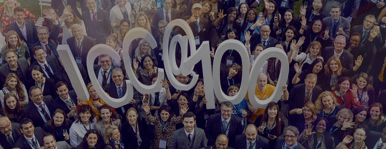A crowd of cheering people holding ${esc.q}ICC @ 100${esc.q} in big singular letters