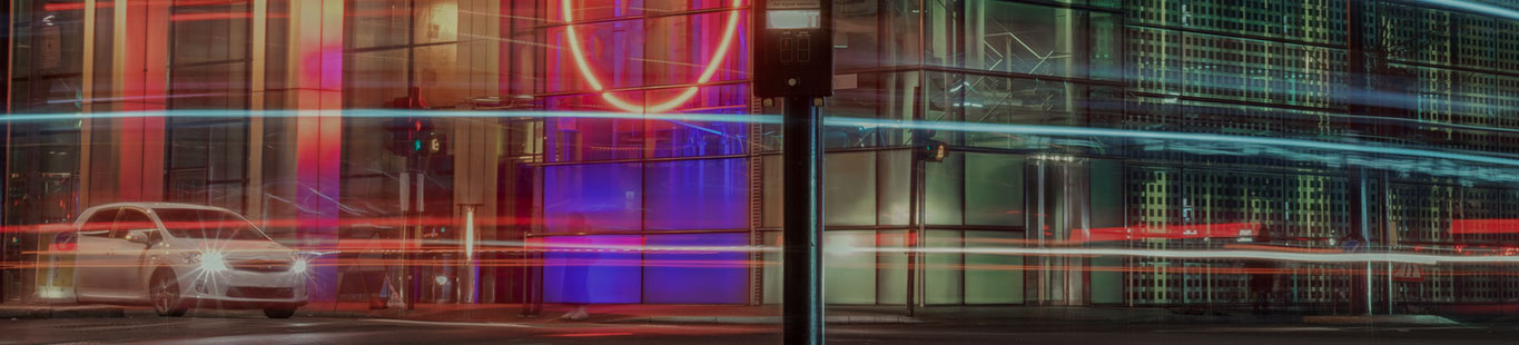 A car at a red light mirrored in a window at night