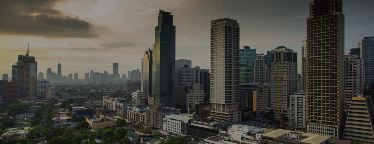 Morning sun shining through clouds onto low and high rise buildings in Makati, Manila Region