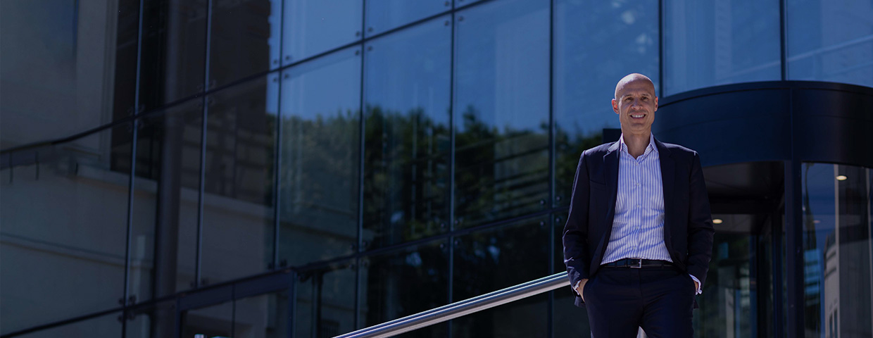 man wearing a suit in front of a glas building