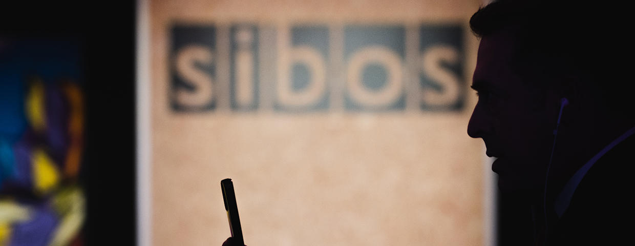 A person with a smartphone in front of a sibos image