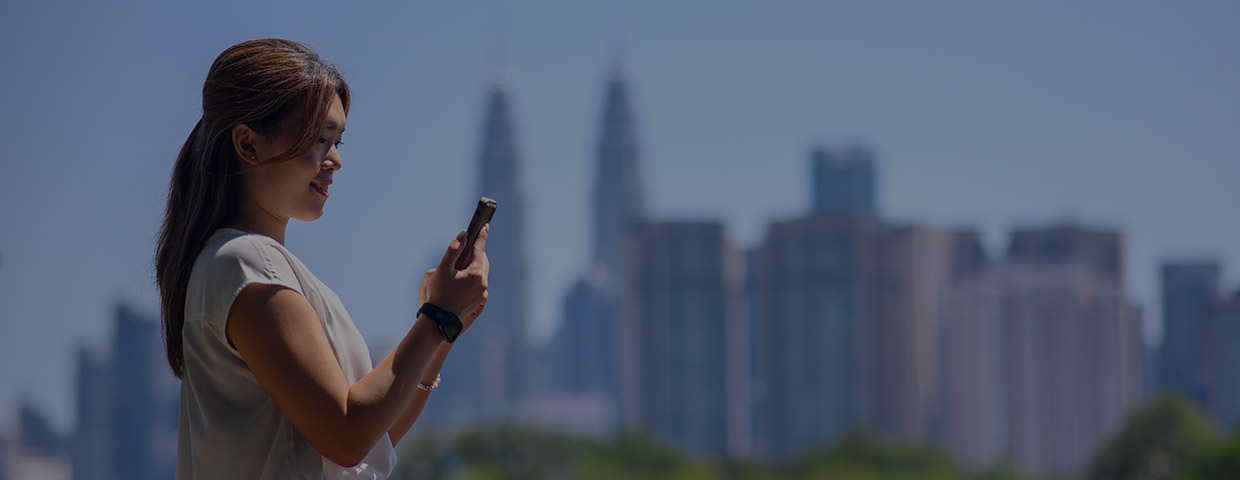 Asian woman holding her phone before a skyline