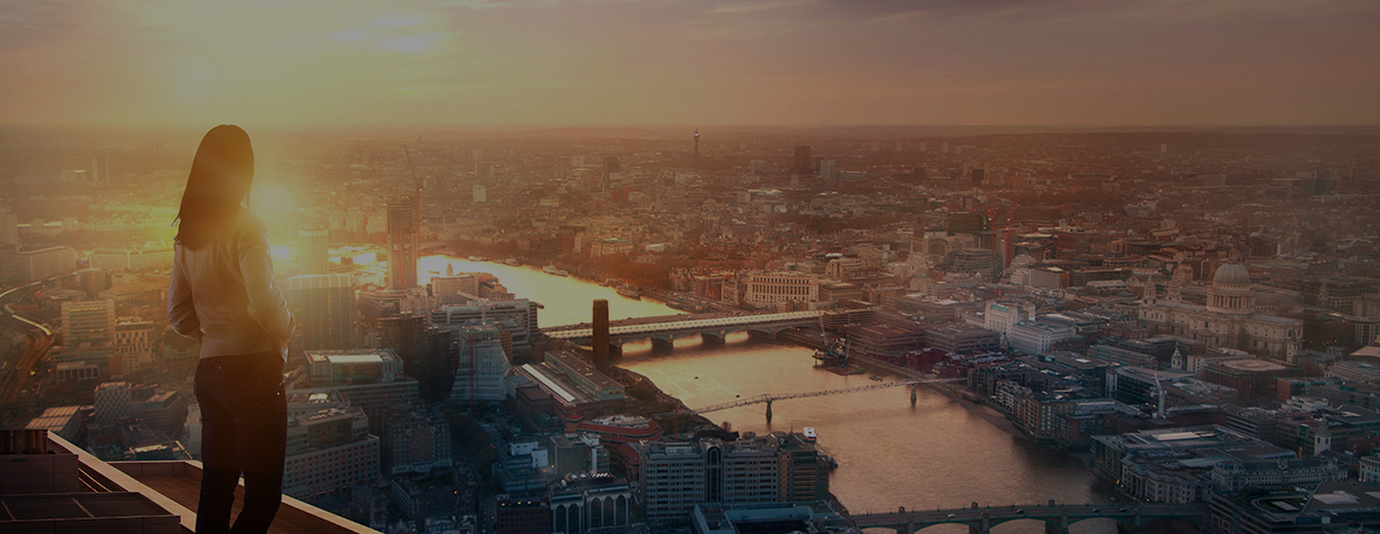 Young woman looking over the city of London at sunset