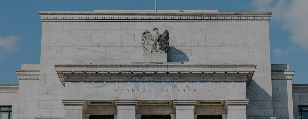 Closeup of Federal Reserve bank facade entrance, architecture building, eagle statue American flags, blue sky at sunny day