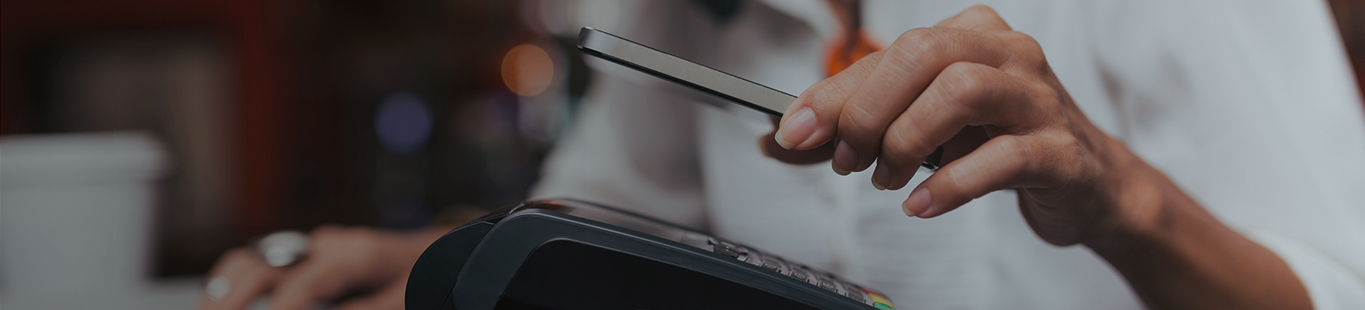 Close-up of a woman paying with her smartphone at a card machine