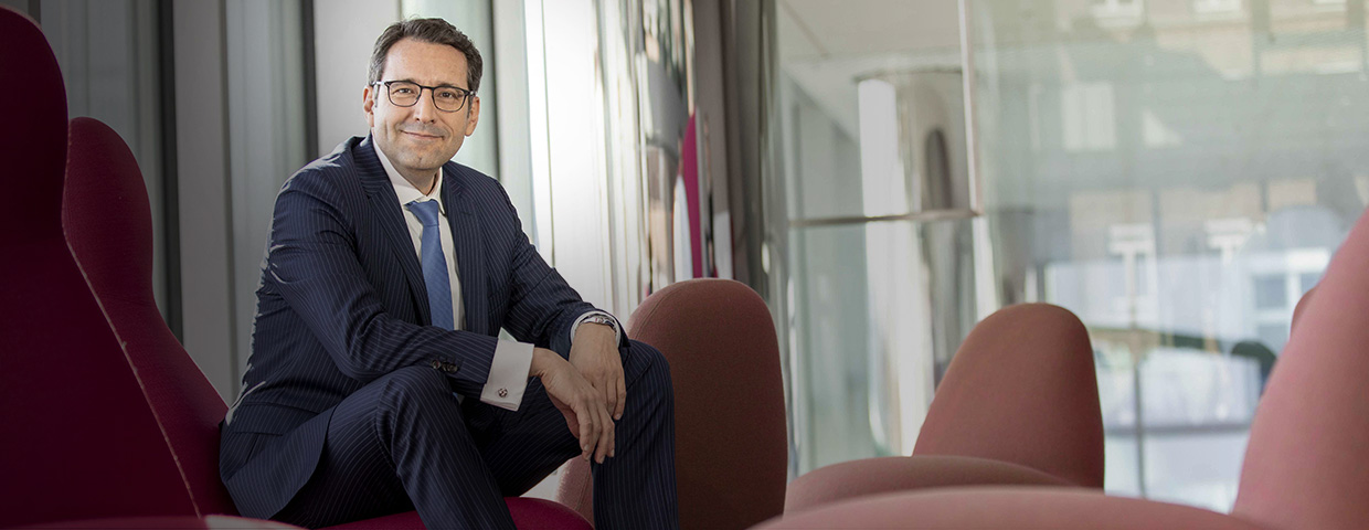 Jörg Bermüller, Head of Cash and Risk Management in Group Treasury, Merck sitting on a red chair in a glass building