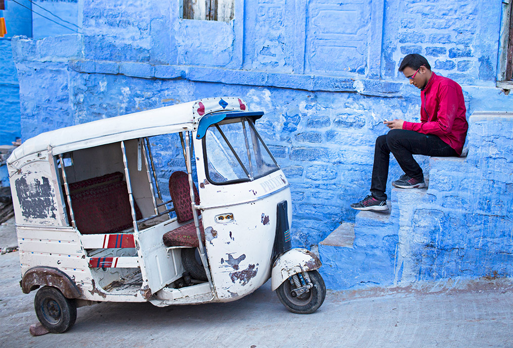 Young man texting a message next to his rickshaw at Jodhpur