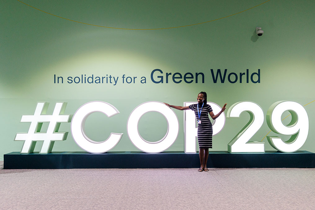 a woman standing in front of a COP29 shield