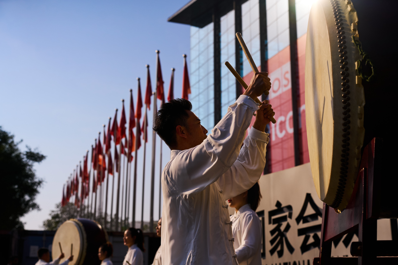 Man holding drumsticks in front of a gong