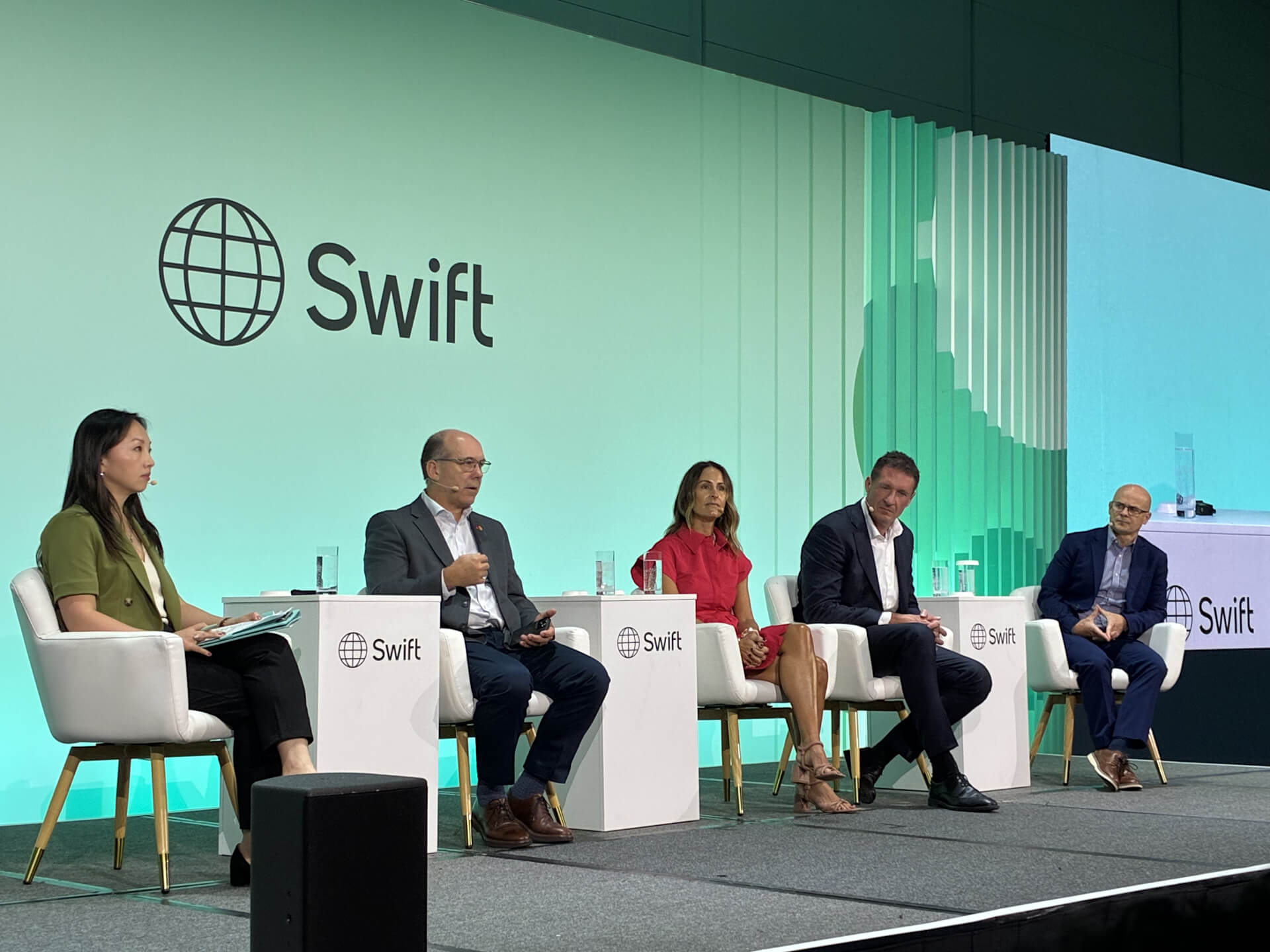 A panel of five speakers, two women and three men, during a business talk at a Swift event